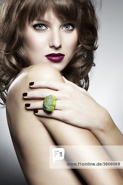 Portrait einer jungen Frau mit einem Ring aus Brokkoli  Schmuck  mit einem verführerischen Blick