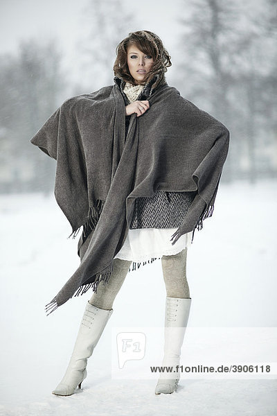Young woman in the snow  wrapped in a poncho