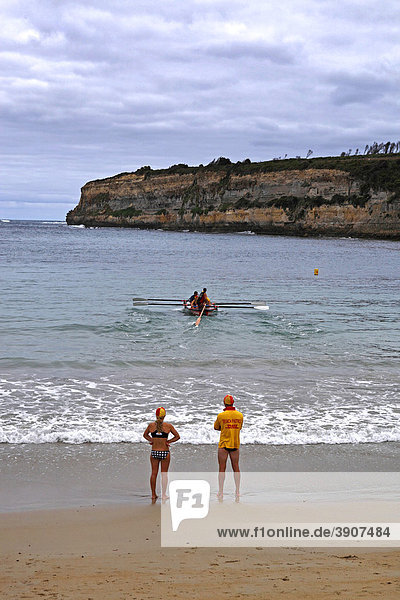 Strandwächter stehen am Sandstrand und beobachten ein Rettungsboot in der Ausbildung bei Übungen  Port Campbell  Victoria  Australien