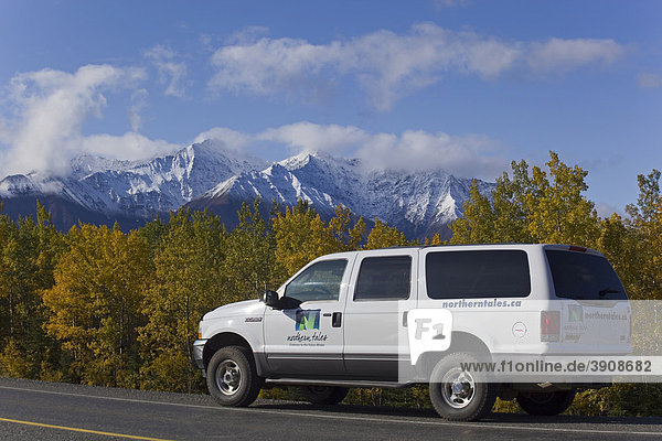 Geländewagen fährt auf dem Alaska Highway  Indian Summer  Bäume in Herbstfarben  St. Elias Mountains Gebirge dahinter  Kluane Nationalpark und Reservat  Yukon Territory  Kanada