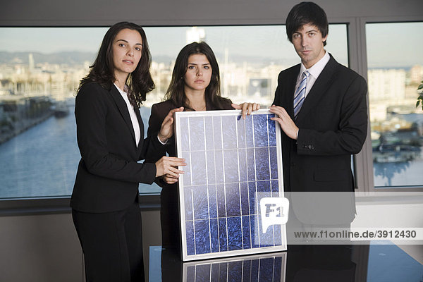Drei Verkäufer mit einem kleinem Solarmodul in einem Büro  direkter Blick