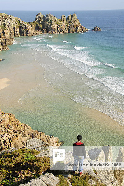 Frau schaut auf Wellen und Strand  Aussichtspunkt  Porthcurno Beach  Pednvounder Beach  Logan Rock  Südküste  Cornwall  England  Großbritannien  Europa