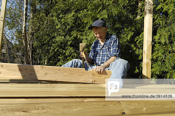 Mann arbeitet mit Stemmeisen am Holzbrett