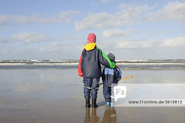 Geschwister  Mädchen  7 Jahre  und Junge  2 Jahre  stehen am Nordseestrand und schauen auf das Meer  Vejers Strand  Jütland  Dänemark  Europa