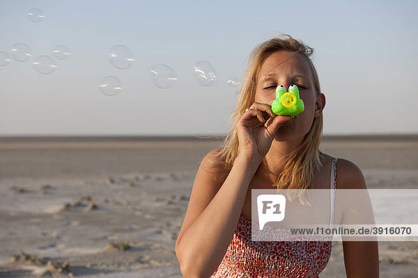 Junge Frau  20-25 Jahre  hat Spaß beim Seifenblasen  St Peter Ording  Nordsee  Nordfriesland  Schleswig-Holstein  Norddeutschland  Deutschland  Europa