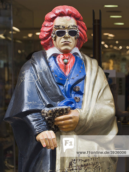 Beethovenstatue mit roten Haaren  Sonnenbrille und bunter Kleidung  dahinter Einzelhandelsgeschäft