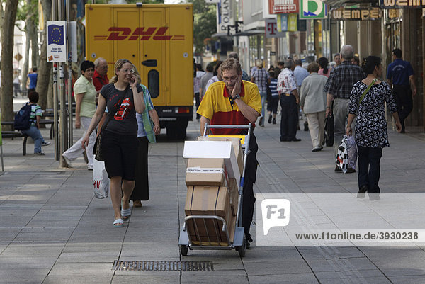 Parcel carrier Michael Meindel balancing a stack of packages across the street with his cart for the Deutsche Post German mail in downtown Stuttgart Baden-Wuerttemberg Germany Europe
