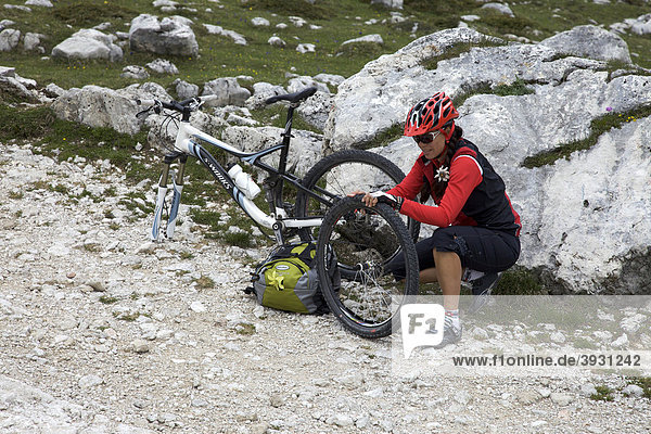 Mountainbike-Fahrerin mit Reifenpanne repariert Vorderrad