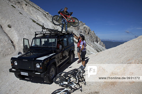 Mountainbike-Fahrerin und Fahrer laden Räder von einem Landrover an der Kreuzjoch-Scharte  Naturpark Fanes-Sennes-Prags  Trentino  Südtirol  Italien  Europa
