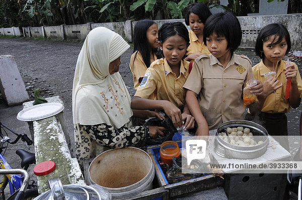 Schüler in Schuluniform in der Pause vor der Schule bei einer moslemischen Straßenhändlerin Yogjakarta  Yogyakarta  Mitteljava  Java  Indonesien  Südostasien