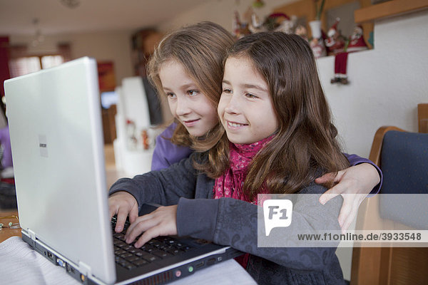 Zwei Mädchen  acht Jahre  mit Laptop