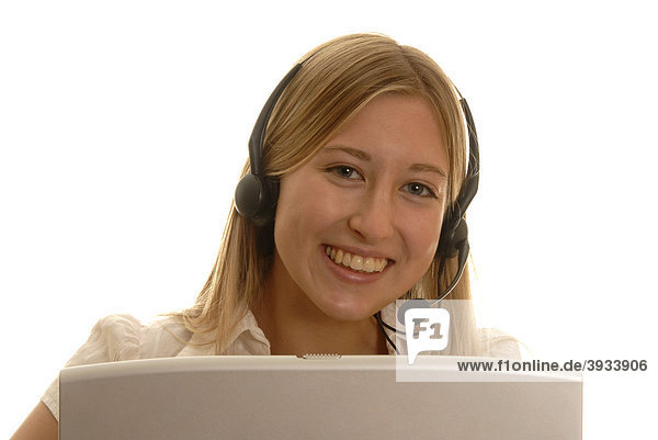 Achtzehnjährige Frau hinter Laptop mit Headset lachend