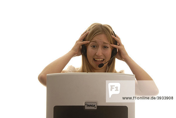 Eighteen year old woman behind a laptop with a headset  laughing  tearing her hair
