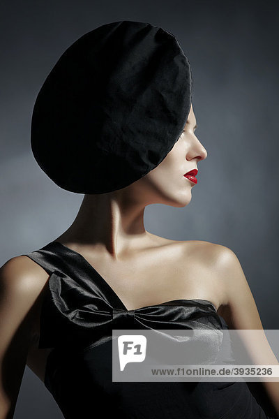 Seitliches Portrait einer jungen Frau im schwarzen Kleid und schwarzem Hut  Fashion