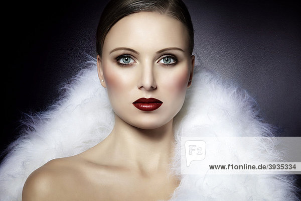 Portrait einer jungen Frau  eingehüllt in ein weißes Fell  tiefroter Lippenstift  direkter Blick  Fashion  Glamour mund