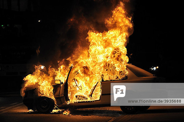 Ein brennendes Auto steht auf einer Straße