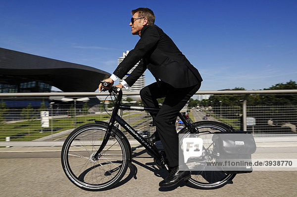 Businessman riding on an electric bicycle  pedelecs  Olympic Stadium  Munich  Bavaria  Germany  Europe