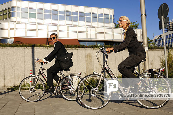 Business people riding on electric bicycles  pedelecs  Hypo-Hochhaus building  Munich  Bavaria  Germany  Europe