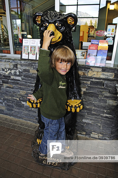 Kind spielt mit Schwarzbären-Figur  Banff Nationalpark  Alberta  Kanada