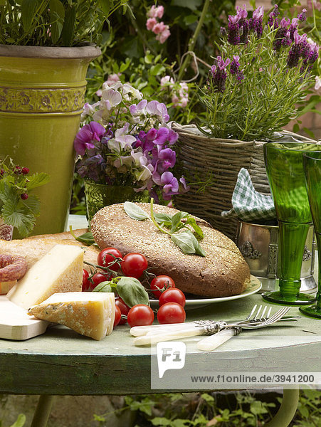 Stillleben mit Brot  Käse und Tomaten auf einem Gartentisch arrangiert