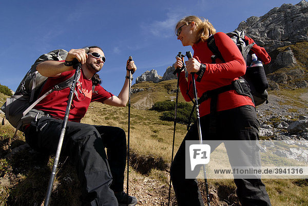 Hikers  woman and man  backpack and trekking poles  taking a break during the ascent to Mt. Heidachstellwand  2192m  Rofan  Achensee  Tyrol  Austria  Europe