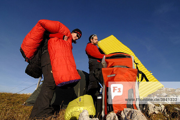 Hikers  young man and woman building a bivouac with tent  sleeping bag  backpack and sleeping pad  Heidachstellwand  Rofan  Achensee  Tyrol  Austria  Europe