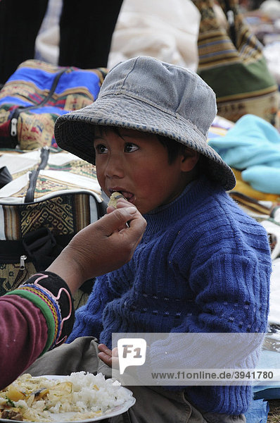 Child being fed at a market  Chinchero  Inca settlement  Quechua settlement  Peru  South America  Latin America
