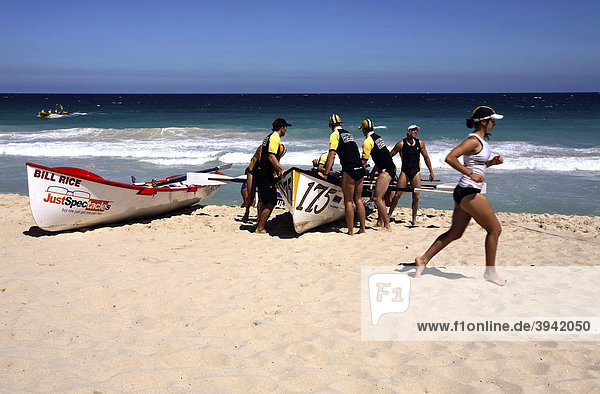 Wettbewerbs-Surfboote und eine laufende Surf Life Saver Rettungsschwimmerin  Scarborough Beach  Perth  Western Australia  Australien