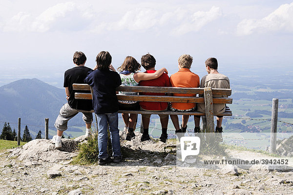 Group of youths sitting on a wooden bench in the Bavarian Alps  Upper Bavaria  Germany  Europe