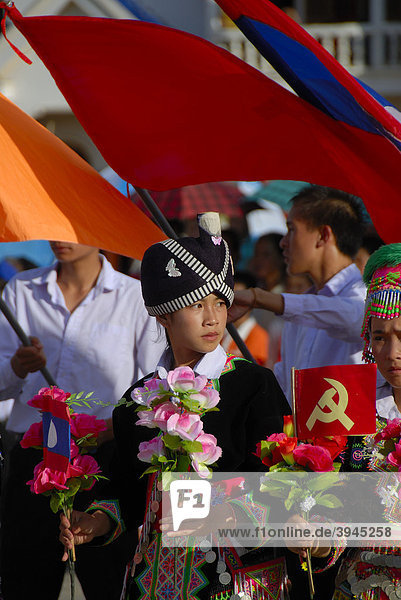 Festival  Hmong girl  dressed in traditional clothing  holding red flags of the Communist Party  national flag of Laos  Xam Neua  Houaphan province  Laos  Southeast Asia  Asia