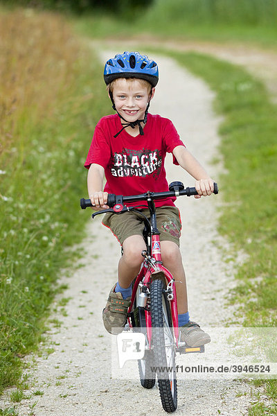 Ein Junge  7 Jahre  mit Fahrrad  auf einem Feldweg