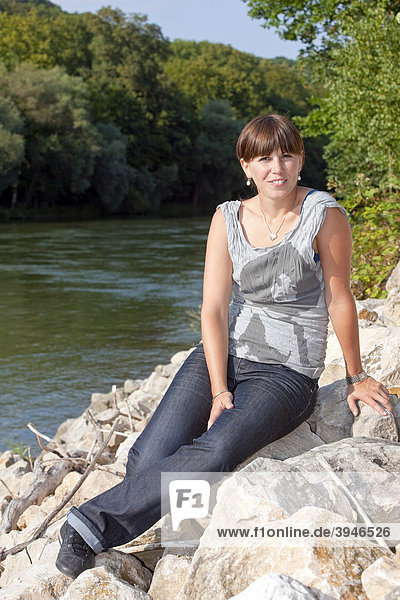 Eine junge Frau sitzt an einem Fluss