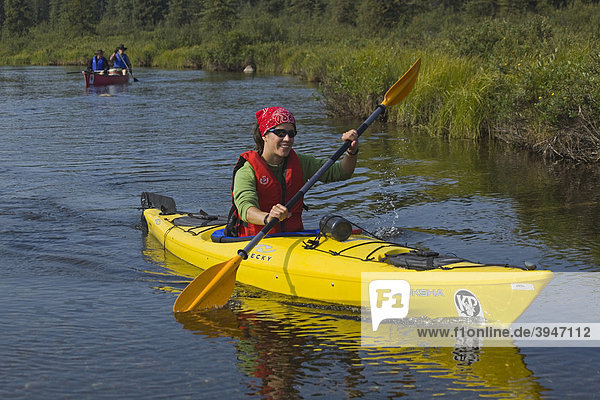 Young woman in kayak  paddling  kayaking  clear  shallow water of Caribou Creek  upper Liard River  Yukon Territory  Canada