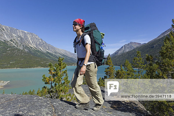 Young woman hiking  backpacking  hiker with backpack  historic Chilkoot Trail  Chilkoot Pass  Lake Bennett behind  Yukon Territory  British Columbia  B. C.  Canada