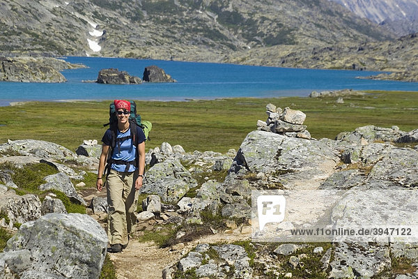 Young woman hiking  backpacking  hiker with backpack  historic Chilkoot Trail  Chilkoot Pass  Crater Lake behind  alpine tundra  Yukon Territory  British Columbia  B. C.  Canada