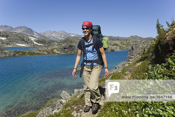 Young woman hiking  backpacking  hiker with backpack  historic Chilkoot Pass  Chilkoot Trail  Crater Lake behind  alpine tundra  Yukon Territory  British Columbia  B. C.  Canada