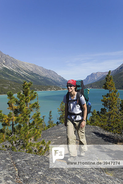 Young woman hiking  backpacking  hiker with backpack  historic Chilkoot Pass  Chilkoot Trail  Lake Bennett behind  Yukon Territory  British Columbia  B. C.  Canada
