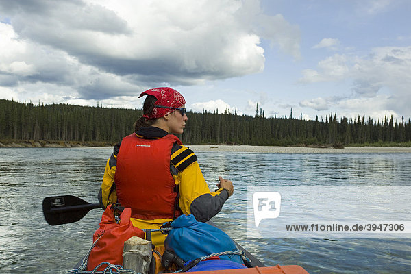 Junge Frau paddelt in einem Kajak  Kajakfahren  oberer Liard River  Yukon Territory  Kanada