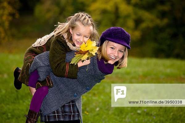 Two sisters playing in a park in autumn