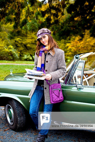 Young woman with a newspaper leaning against a vintage car  MB 220 SE Cabriolet  built in 1964
