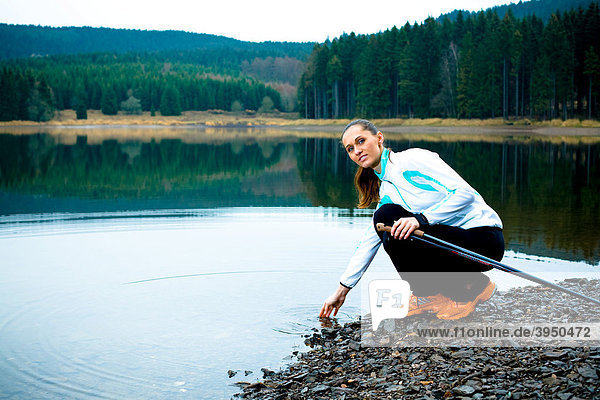 Junge Frau macht Pause bei einer Wanderung am See