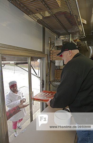 Workers distribute free pizza to the hungry from the Little Caesars Love Kitchen  a mobile kitchen parked outside the All Saints Catholic Church soup kitchen  operated by the Little Caesars pizza chain  Detroit  Michigan  USA