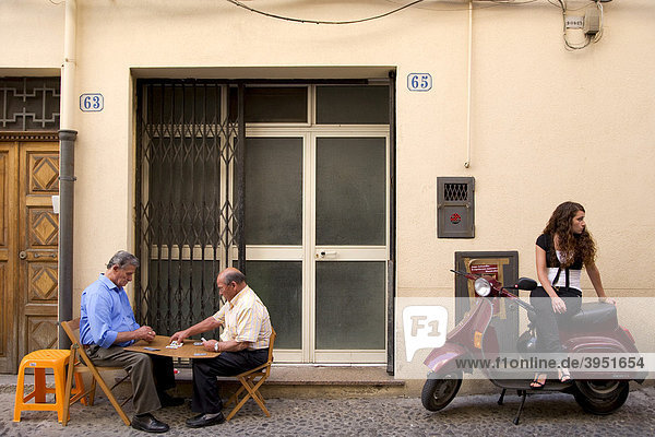Straßenszene Männer spielen Karten Mädchen sitzt auf Vespa Cefalu Provinz Palermo Sizilien Italien Europa