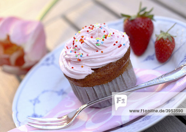 Cupcake Muffin mit Sahne  Zuckerstreuseln und Erdbeeren auf Teller