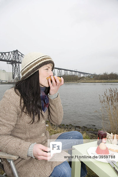 Young woman  30-35 years  having breakfast on a damp winter day at the Kiel Canal  waiting for passing ships  Schleswig-Holstein  Germany  Europe