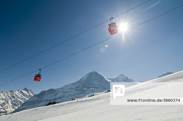Moench and Eiger mountains and a gondola lift with backlighting from the sun  Grindelwald  Switzerland  Europe