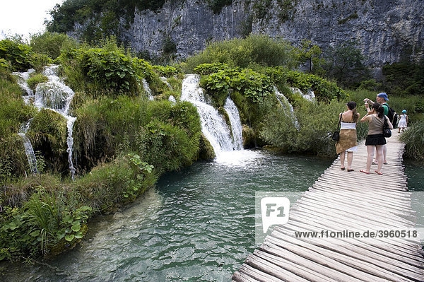 Tourists in front of a small waterfall in the cascade landscape of the Plitvice Lakes  Plitvice Lakes National Park  Croatia  Europe