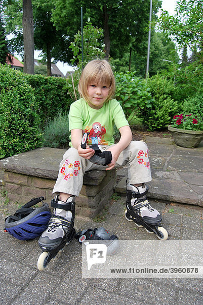Mädchen  5 Jahre  zieht Arm- und Knieschoner an  Vorbereitung und Vorsorge treffen zum Inline-Skaten