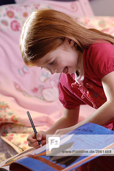 Kleines Mädchen hält einen Stift in den Händen und schreibt  malt