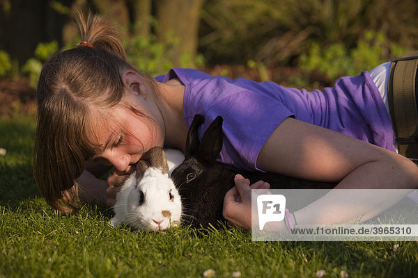 Junges Mädchen spielt mit zwei Kaninchen auf einer Wiese